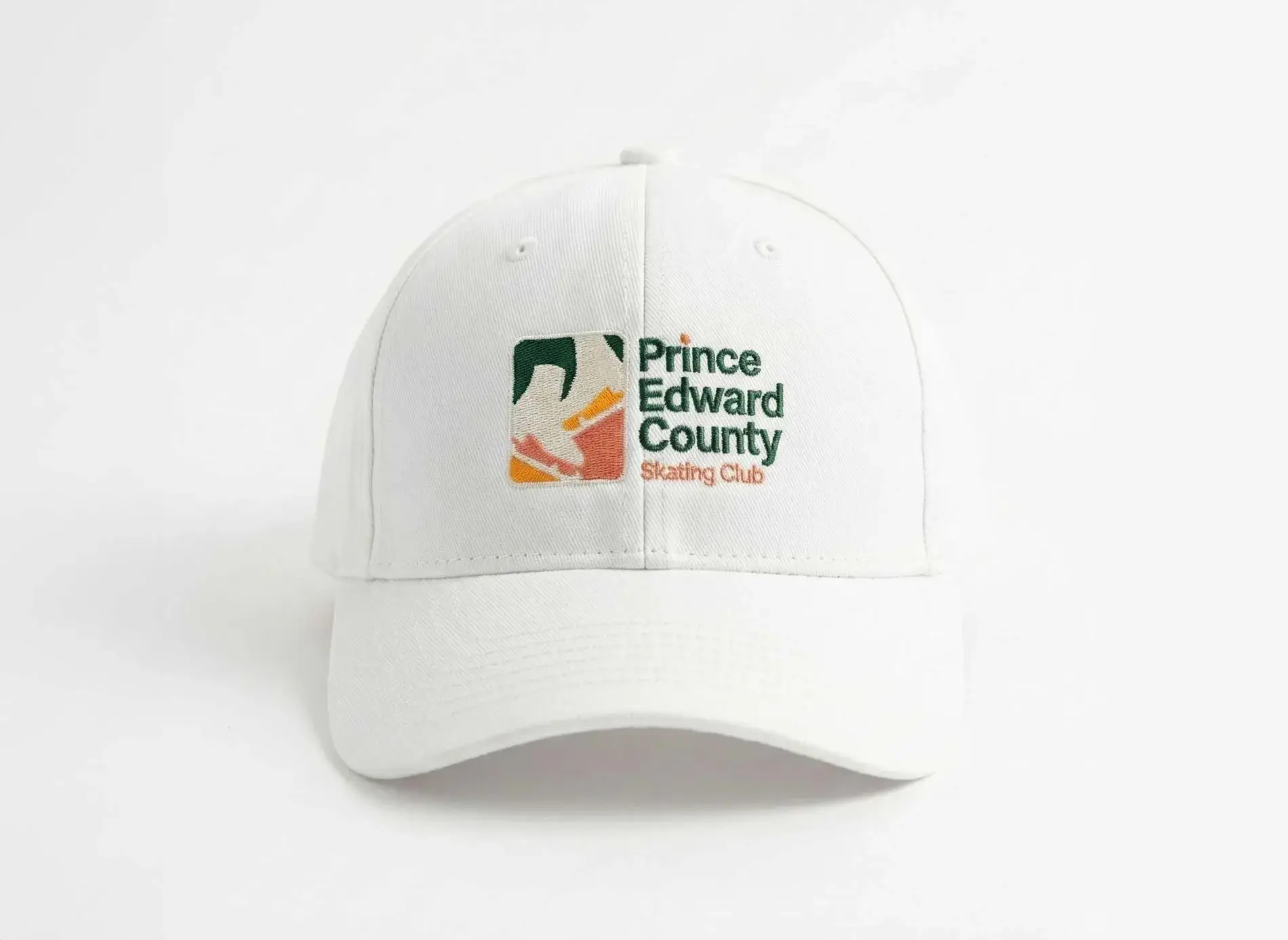 White cap with the embroidered Prince Edward County Skating Club logo
